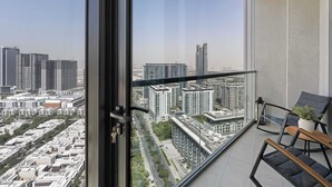 Un balcón con vista a un paisaje urbano, que incluye edificios altos y una carretera.