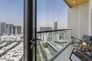 A balcony with a view of a cityscape, including high-rise buildings and a road. - Cozy 1BR Retreat,  Prime Location (Dubai)