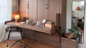 A modern office desk with a lamp, clock, and storage boxes.