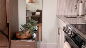A kitchen with a refrigerator, a sink, and a mirror.