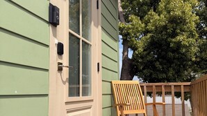 A wooden deck with a door, a bench, and a small table.