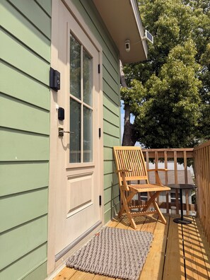 Una terraza de madera con una puerta, un banco y una pequeña mesa.