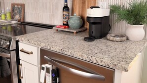A modern kitchen with stainless steel appliances, a granite countertop, and a welcome sign.
