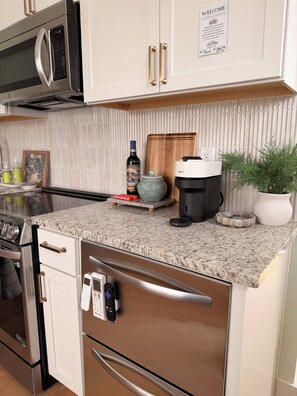 Una cocina moderna con electrodomésticos de acero inoxidable, encimera de granito y un letrero de bienvenida.