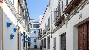 A narrow cobblestone street flanked by white buildings with balconies and wooden doors. - Genteel Home Almanzor (Cordoba)