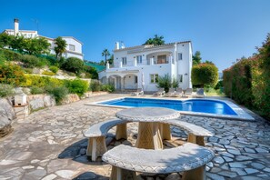 A white villa with a swimming pool, stone patio, and outdoor seating. - Villa Friesland – Pleasant Villa with Pool in a Peaceful Setting (Calonge)