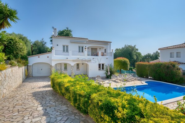 A two-story house with a swimming pool, stone pathway, and lush greenery. - Villa Friesland – Pleasant Villa with Pool in a Peaceful Setting (Calonge)