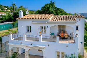 A two-story house with a balcony, a terrace, and a view of the surrounding greenery. - Villa Friesland – Pleasant Villa with Pool in a Peaceful Setting (Calonge)