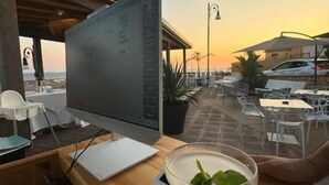 A computer monitor on a wooden table with a drink in front. - Paguro Beach Hotel  (Siculiana Marina)
