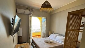 A bedroom with a bed, bedside table, TV, and a wooden chair. - Paguro Beach Hotel  (Siculiana Marina)