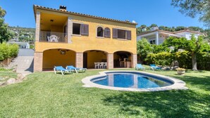 Ein zweigeschossiges Haus mit Swimmingpool, Sitzgelegenheiten im Freien und einem Garten.