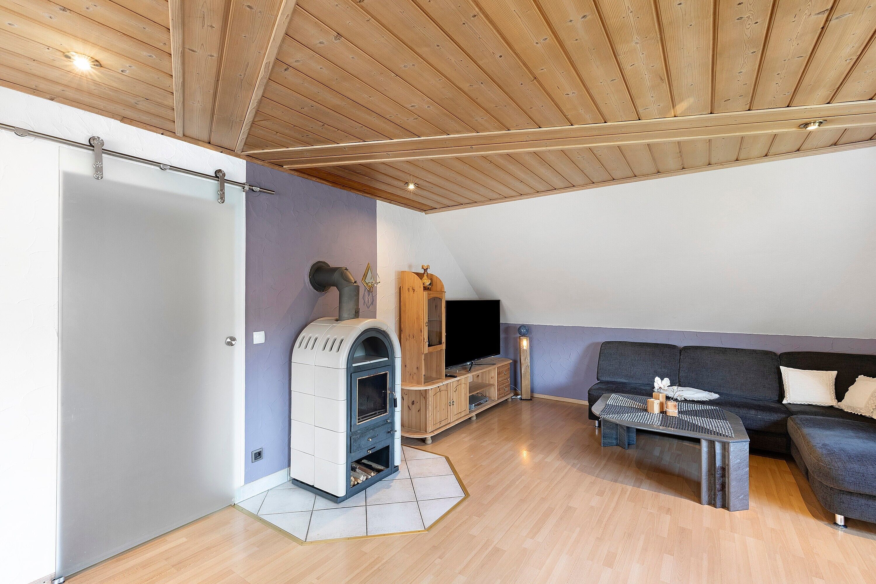 Un salon avec une cheminée, un canapé, une télévision et un plancher en bois.