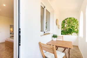 Ein Zimmer mit Holztisch und -stühlen, einem Blumentopf und einem Fenster mit Blick auf Grünflächen.