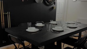 A dining area with a black table, chairs, and a dartboard on the wall. - The Coach House - ultimate home away from home! (Huddersfield)