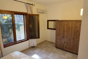 Une chambre avec un lit, une fenêtre avec des rideaux, une armoire en bois et un appareil de climatisation.