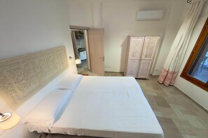 A bedroom with a bed, a wardrobe, a mirror, and a window. - Abbaechelu to Santa Margherita Pula (Pula (CA))