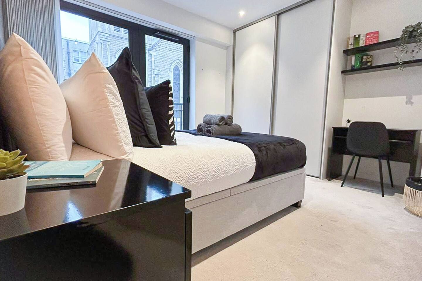 Une chambre à coucher moderne, avec un lit, une table de chevet et un espace bureau.