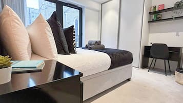 Une chambre à coucher moderne, avec un lit, une table de chevet et un espace bureau.