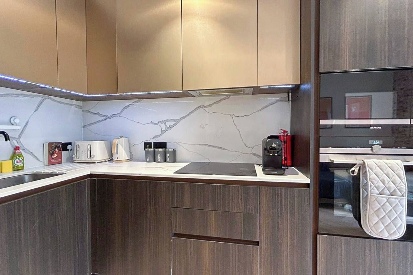 Eine moderne Küche mit dunklen Holzschränken, einer Marmor-Spritzschutzwand und einem Siemens-Kühlschrank.