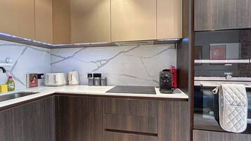 Eine moderne Küche mit dunklen Holzschränken, einer Marmor-Spritzschutzwand und einem Siemens-Kühlschrank.