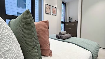 A bedroom with a bed, pillows, a dresser, and a window.