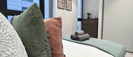 Un dormitorio con cama, almohadas, cómoda y ventana.