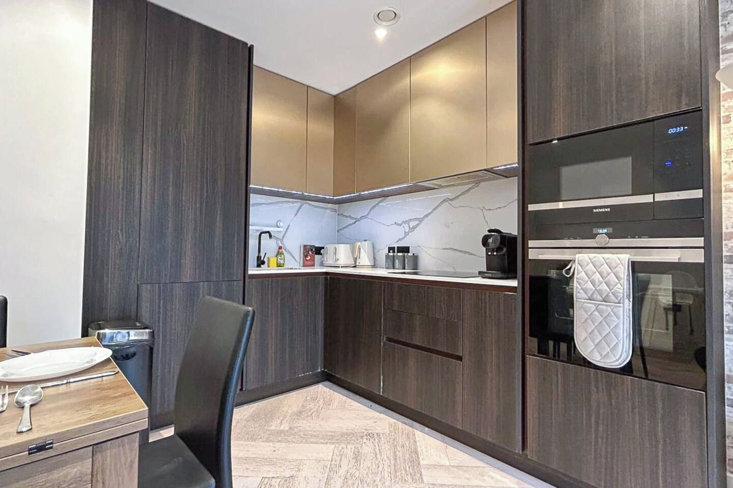 A modern kitchen with dark wood cabinets, a marble backsplash, and a Siemens oven.