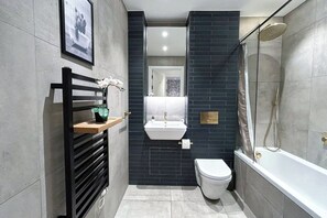 Un baño moderno con inodoro blanco, lavamanos y ducha.