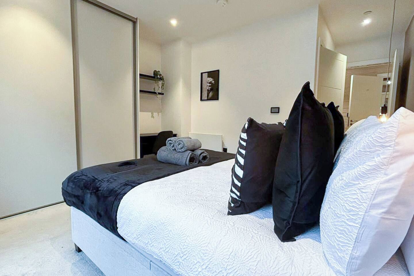 A modern hotel room with a large bed, a desk, and a chair.