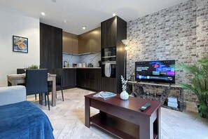 A modern living room with a TV, a dining area, and a kitchen. - Furnished Apt Near Tower Bridge & aldgate station (London)