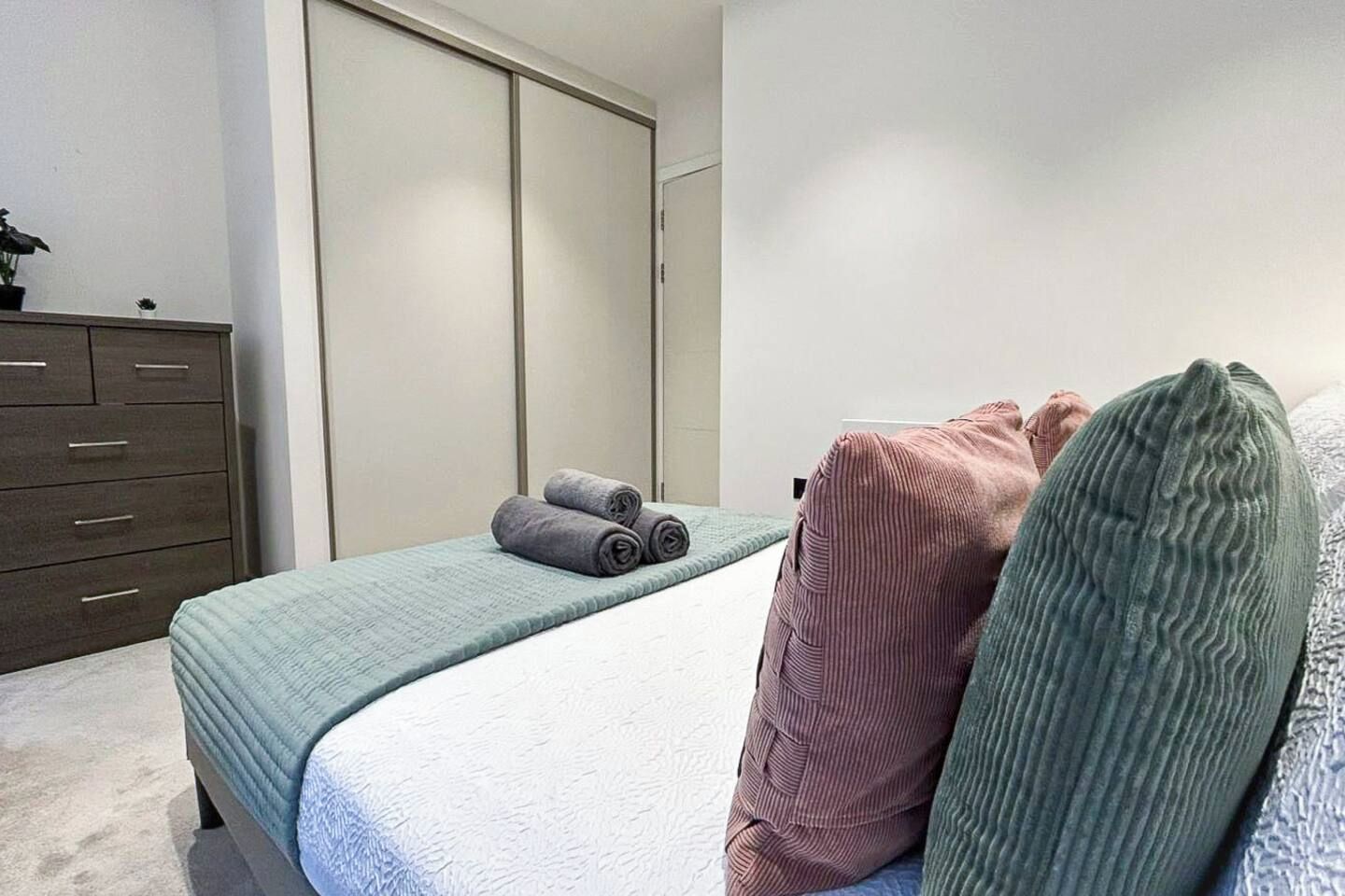 A bedroom with a bed, a dresser, and a closet.