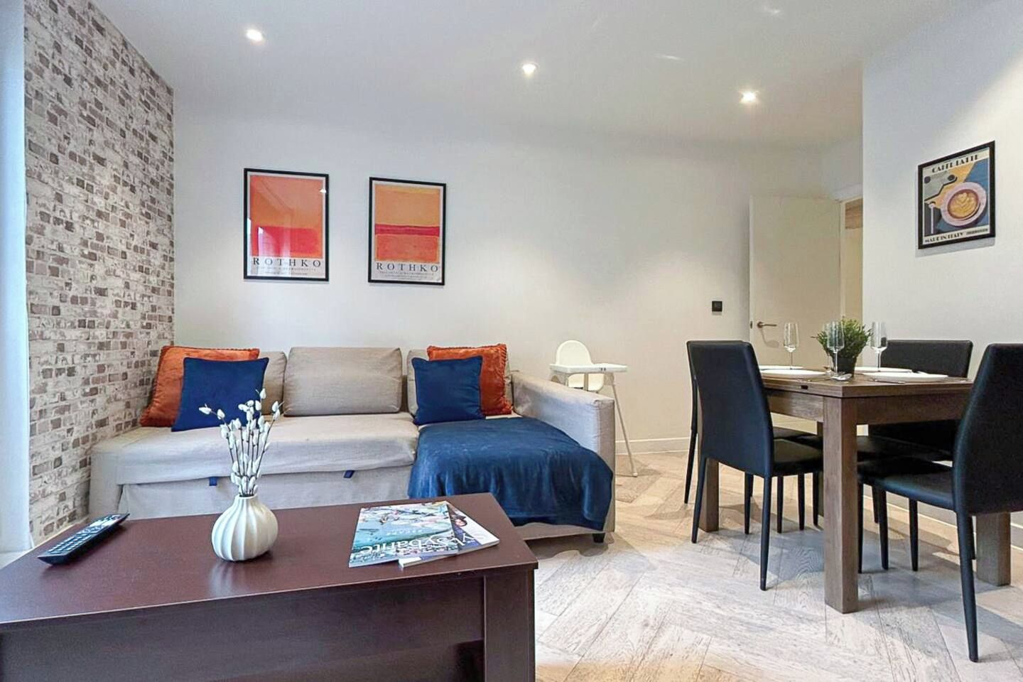 A living room with a sofa, coffee table, and a dining area with chairs and a table.