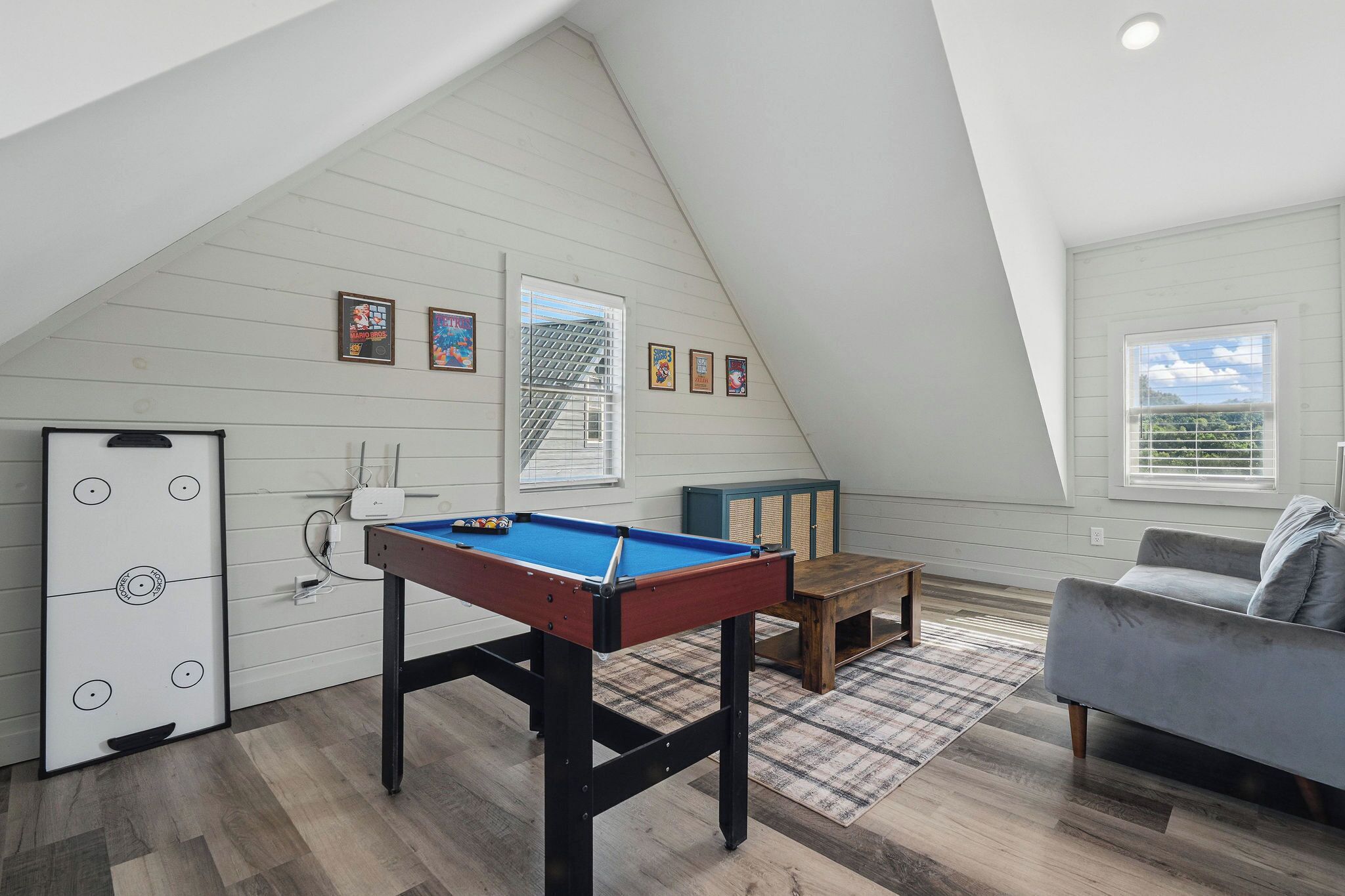 Une pièce de style loft avec une table de billard, un canapé et un meuble.