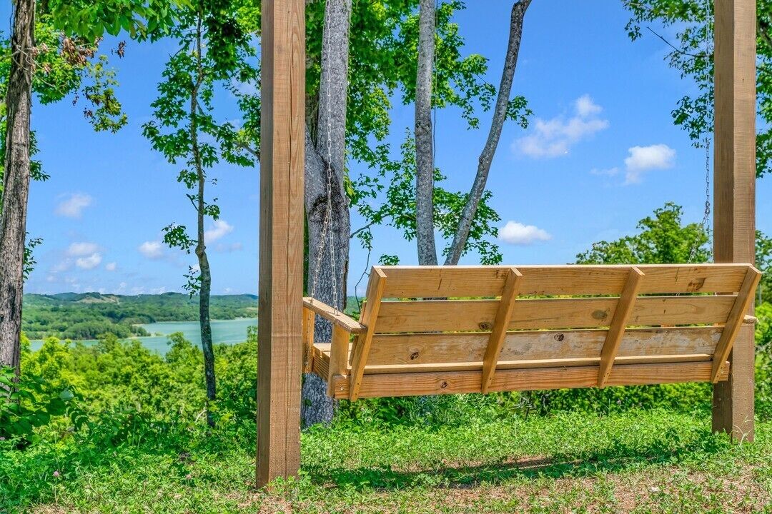 Un banc en bois, placé dans un environnement naturel, entouré d’arbres et offrant une vue sur un paysage.
