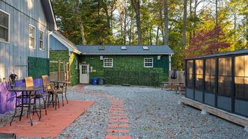 A patio area with a gravel path, a table with chairs, and a building with a green ivy-covered wall.