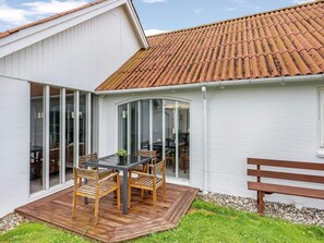 A modern house with a patio, a dining table, and chairs. - 4 Star Holiday Home in Lokken (Lokken)