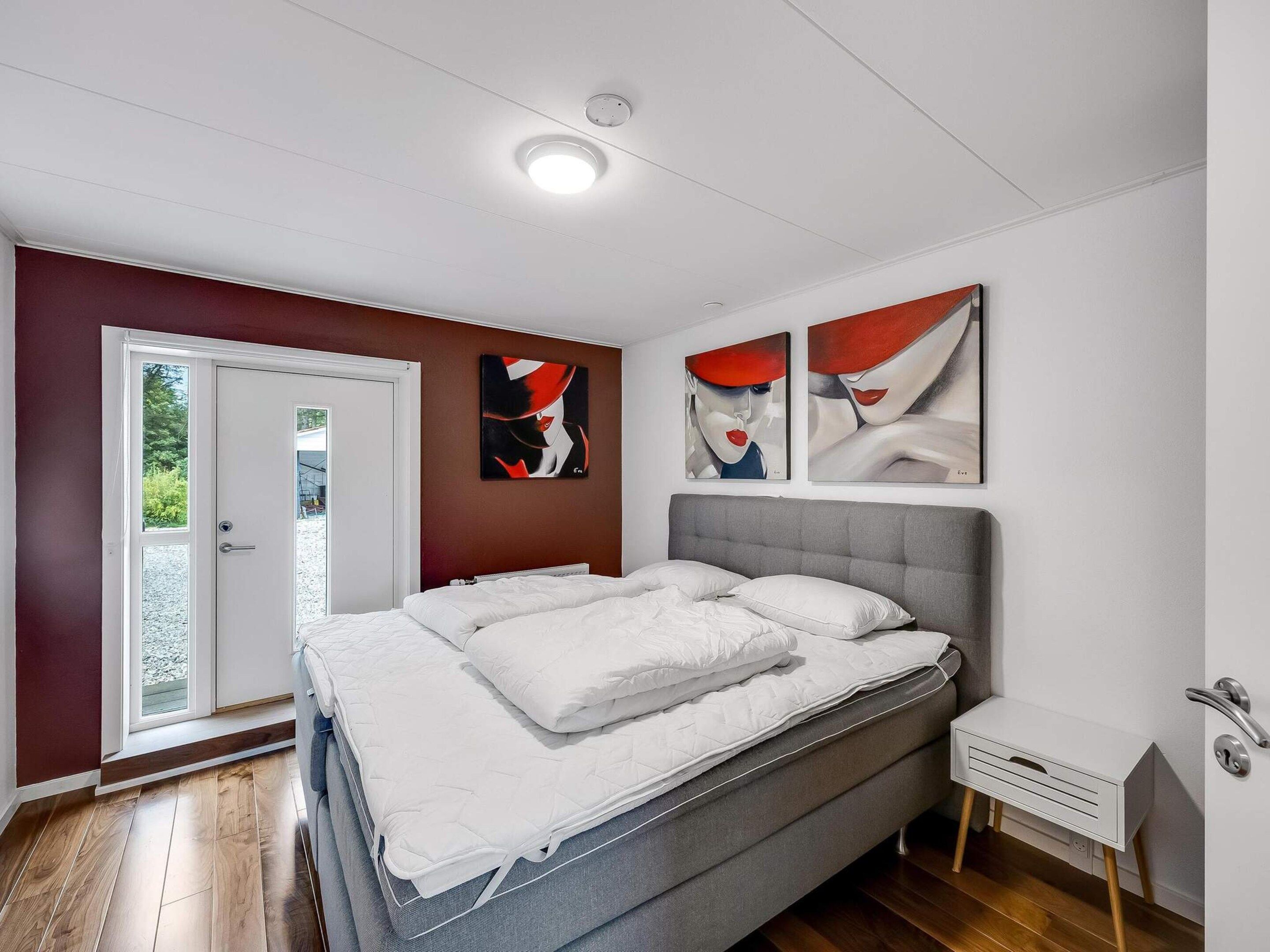 Una camera da letto con un letto, un comodino, una porta e arte astratta alle pareti.