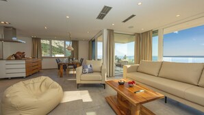 Una sala de estar moderna con un sofá, un sillón de felpa, una mesa de centro de madera y una zona de comedor con una mesa y sillas.