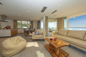 A modern living room with a sofa, a bean bag, a wooden coffee table, and a dining area with a table and chairs. - Exclusive Penthouse Sara with 3 Bedrooms, Sea View, Hot Tub & Modern Luxury (Makarska)