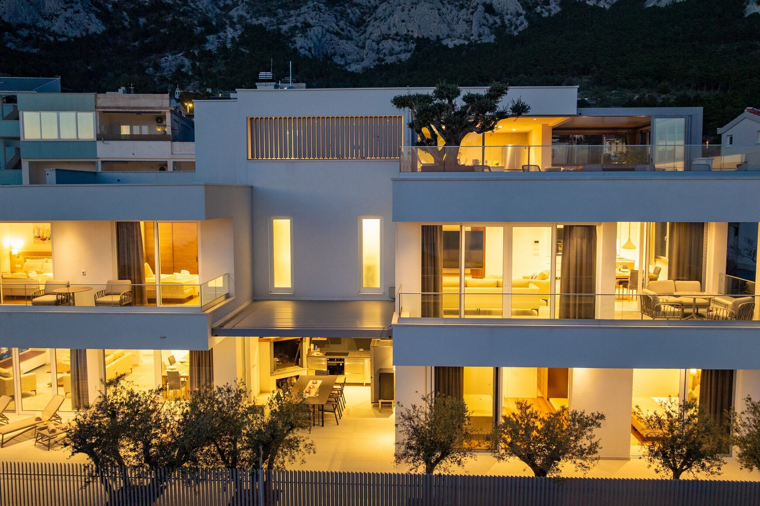 A modern multi-story residential building with balconies, large windows, and a well-lit interior.