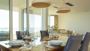 Un comedor con una mesa de vidrio, sillas y copas de vino.