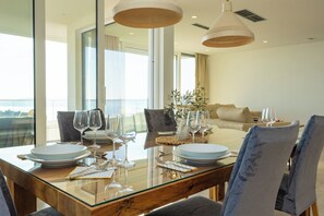 A dining area with a glass table, chairs, and wine glasses. - Exclusive Penthouse Sara with 3 Bedrooms, Sea View, Hot Tub & Modern Luxury (Makarska)