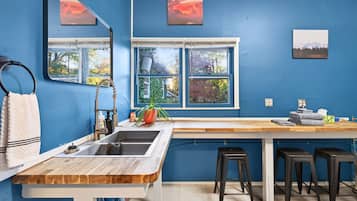 A modern kitchen with a wooden countertop, a sink, and bar stools.