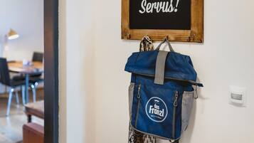Una habitación con un cartel en la pared que dice 'Servus!' y una mochila azul colgada de un gancho.