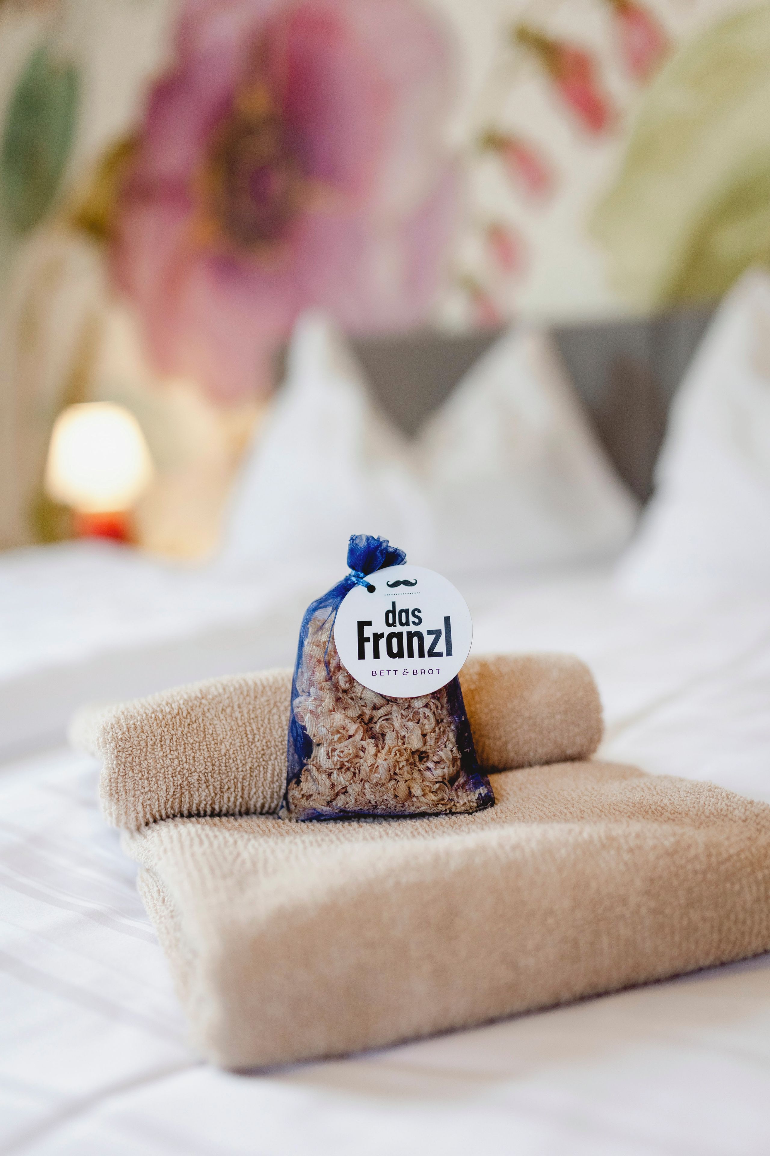 Un lit bien fait, avec une étiquette portant l’inscription « das Franzl » sur une serviette beige.