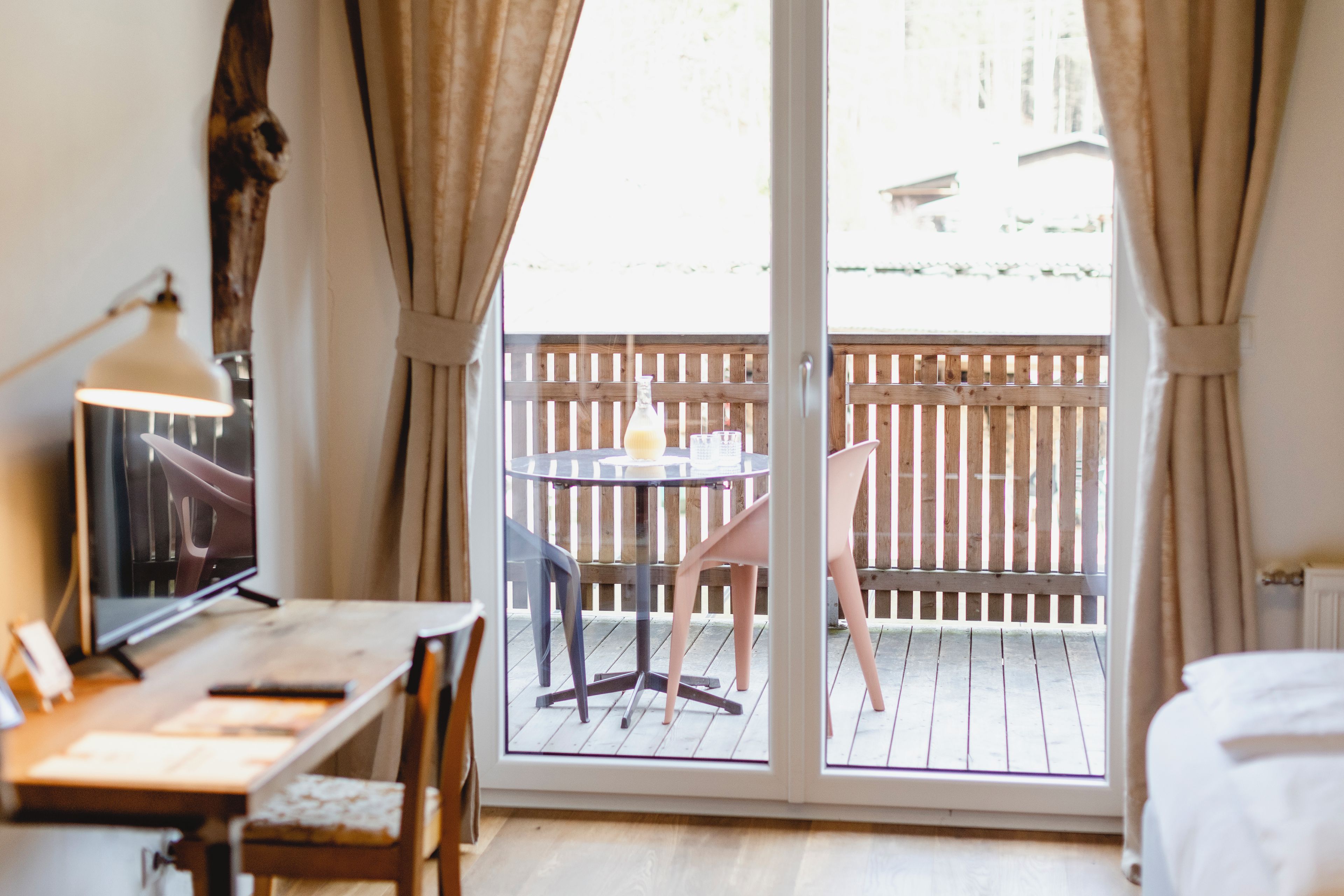 A room with a desk, chair, and a view of a wooden deck outside.