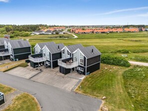 A residential area with modern houses, a paved driveway, and a grassy field. - 4 Star Holiday Home in Lokken (Lokken)