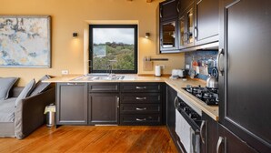 A modern kitchen with dark cabinetry, a wooden countertop, a built-in stove, and a window offering a view of greenery. - Holiday Home 'La Torre' with Private Terrace, Private Garden and Wi-Fi (Santa Cruz de Tenerife)