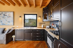 Una cocina moderna con armarios oscuros, encimera de madera, horno integrado y ventana con vistas al verdor.