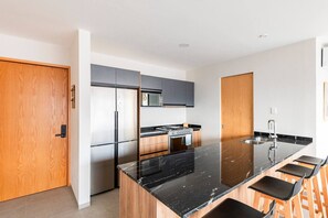 Eine moderne Küche mit einer schwarzen Marmorinsel, Edelstahlgeräten und Holzschränken.